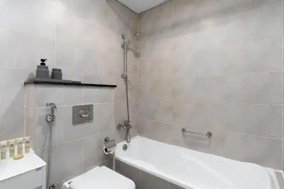 a bathroom with a bath tub and a toilet at Maison Privee - Refined Studio with Top Facilities in Damac Hills in Dubai