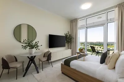 a bedroom with a bed and a table and a tv at Maison Privee - Refined Studio with Top Facilities in Damac Hills in Dubai