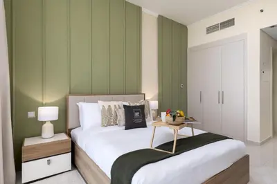 a bedroom with a bed with a table on it at Maison Privee - Refined Studio with Top Facilities in Damac Hills in Dubai