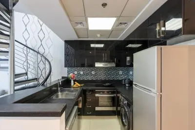 a kitchen with black counters and a white refrigerator at Urban Haven - Peaceful Sanctuary - City Loft in Dubai