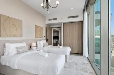 two white beds in a room with a window at Stylish 2 Bedroom with Panoramic canal View in Dubai