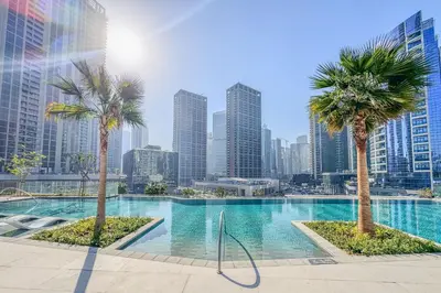 a swimming pool with palm trees in a city at Stylish 2 Bedroom with Panoramic canal View in Dubai