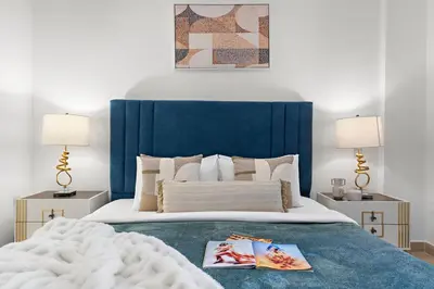 a bed with a blue headboard and two lamps at The Smart Concierge - Andalus Jumeirah Golf Estates in Dubai