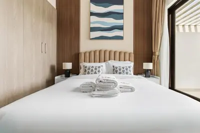 a large white bed with two towels on it at Family Retreat 3BR Greenwoods Villa in DAMAC Hills in Dubai