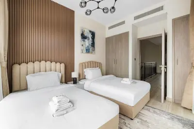 a bedroom with two beds and a chandelier at Family Retreat 3BR Greenwoods Villa in DAMAC Hills in Dubai
