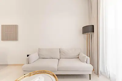 a white living room with a couch and a lamp at HAVN - 3 bedroom in Binghatti Crest, JVC in Dubai