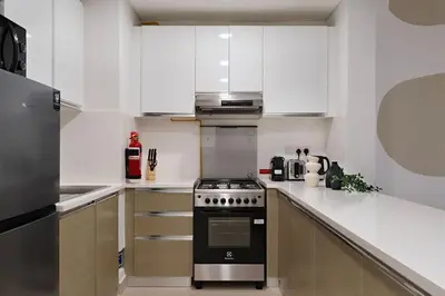 a kitchen with white cabinets and a stove top oven at The Smart Concierge - Andalus Jumeirah Golf Estates in Dubai