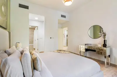 a white bedroom with a large bed and a desk at The Smart Concierge - Andalus Jumeirah Golf Estates in Dubai