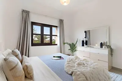 a white bedroom with a bed and a mirror at The Smart Concierge - Andalus Jumeirah Golf Estates in Dubai