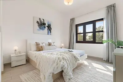 a white bedroom with a large bed and a window at The Smart Concierge - Andalus Jumeirah Golf Estates in Dubai
