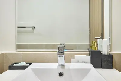 a bathroom sink with a faucet in front of a mirror at Modern 2BR Apartment with Zabeel Park & Skyline Views in Dubai