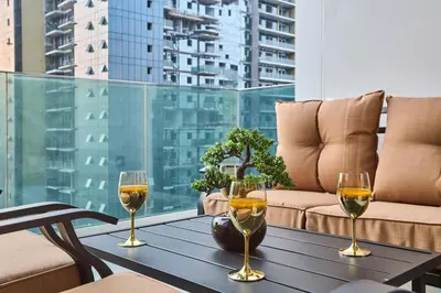 a table with three glasses of wine on a balcony at Modern 2BR Apartment with Zabeel Park & Skyline Views in Dubai