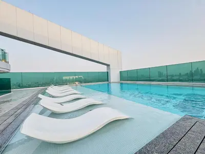 a swimming pool with white chairs in front of a building at Modern 2BR Apartment with Zabeel Park & Skyline Views in Dubai