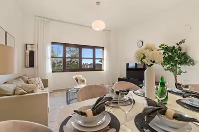 a dining room with a table and a living room at The Smart Concierge - Andalus Jumeirah Golf Estates in Dubai