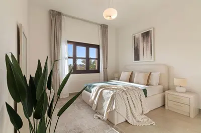 a white bedroom with a bed and a plant at The Smart Concierge - Andalus Jumeirah Golf Estates in Dubai