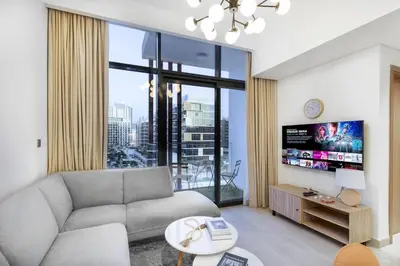 a living room with a couch and a tv at Cozy 1BR with Pool & Gym l 15mn to Downtown in Dubai