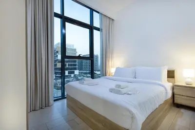 a bedroom with a large white bed with a large window at Cozy 1BR with Pool & Gym l 15mn to Downtown in Dubai