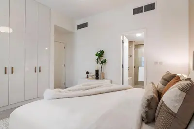 a white bedroom with white walls and a large bed at The Smart Concierge - Andalus Jumeirah Golf Estates in Dubai