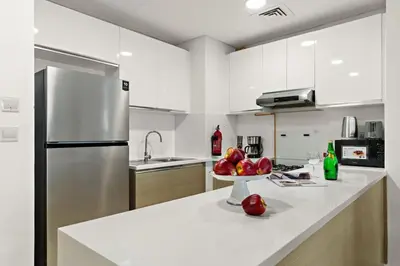 a white kitchen with a bowl of fruit on a counter at The Smart Concierge - Andalus Jumeirah Golf Estates in Dubai