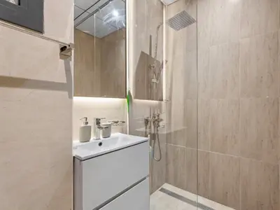 a bathroom with a white sink and a shower at Warm Glow Retreat Cozy Studio In Regina JVC in Dubai