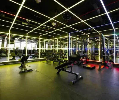 a gym with cardio equipment in a large room at Warm Glow Retreat Cozy Studio In Regina JVC in Dubai
