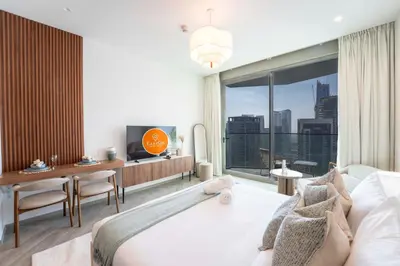 a bedroom with a bed and a desk and a large window at EasyGo - Chic high floor Studio with Burj View in Dubai