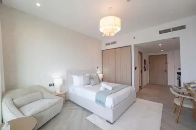 a bedroom with a bed and a chair and a table at EasyGo - Chic high floor Studio with Burj View in Dubai