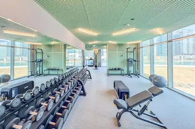 a gym with rows of exercise equipment and large windows at EasyGo - Chic high floor Studio with Burj View in Dubai