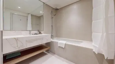 a white bathroom with a tub and a sink and a mirror at Vacationer l Modern 1 Bed l Private Beach l Pool, Gym Access in Dubai