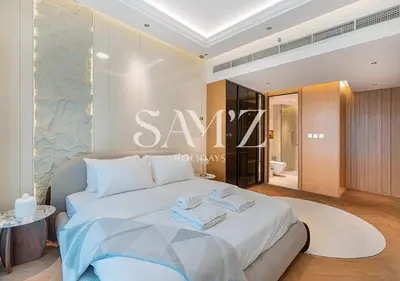 a bedroom with a large bed with a sign on the wall at Stylish 2BR in Downtown Views - High Floor 2906 in Dubai