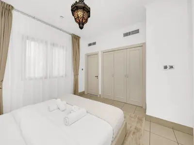a bedroom with a white bed and a chandelier at Luxury 2BR- Pool with Burj View- 5 Min to Dubai Mall in Dubai