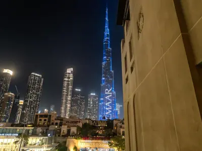 a tall building lit up in blue at night at Luxury 2BR- Pool with Burj View- 5 Min to Dubai Mall in Dubai