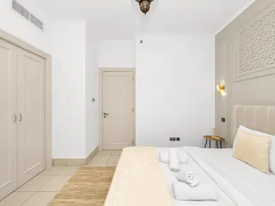 a white bedroom with a large white bed with white furniture at Luxury 2BR- Pool with Burj View- 5 Min to Dubai Mall in Dubai