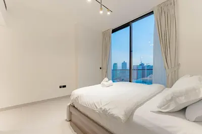 a white bedroom with a large window at HAVN - 2 Bed with Private Pool, JVC in Dubai