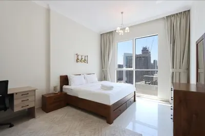 a bedroom with a bed and a desk and a window at Modern 1BR next to Dubai Mall and Burj Khalifa in Dubai