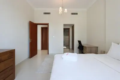 a bedroom with a large white bed and a desk at Modern 1BR next to Dubai Mall and Burj Khalifa in Dubai