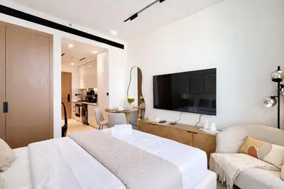 a white bedroom with a large bed and a tv at Modern Studio in Binghatti Azure with Pool & Gym in Dubai