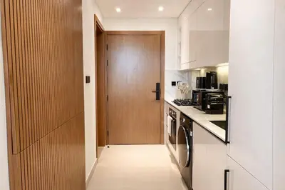a kitchen with a wooden door and a hallway at Modern Studio in Binghatti Azure with Pool & Gym in Dubai