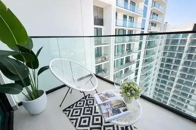 a balcony with two chairs and a table and some plants at Modern Studio in Binghatti Azure with Pool & Gym in Dubai
