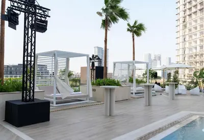a rooftop patio with white chairs and a pool at Binghatti Royale Luxe 1BR W Private Pool Parking in Dubai