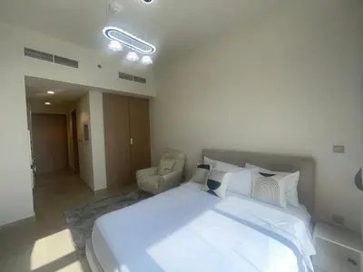 a bedroom with a large white bed and a chair at Studio in Azizi Riviera, 45 in Dubai