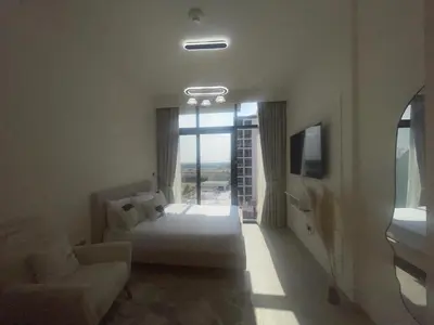 a bedroom with a bed and a couch and a window at Studio in Azizi Riviera, 45 in Dubai