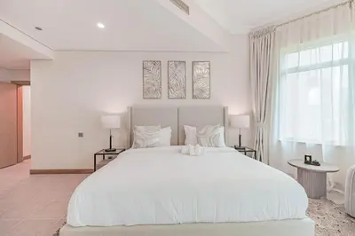 a white bedroom with a large white bed and a window at HAVN - Spacious 2 Bed in Al Hallawi, Palm Jumeirah in Dubai