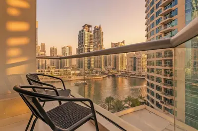 a chair on a balcony with a view of a river at 1 Bedroom Deluxe Apartment with Marina Views in Dubai