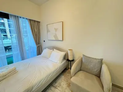 a bedroom with a bed and a chair and a window at Azizi 26 - Unique Studio for Work and Vacation in Dubai