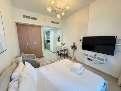 a living room with a white couch and a flat screen tv at Azizi 26 - Unique Studio for Work and Vacation in Dubai