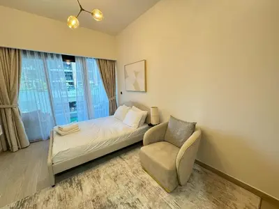 a bedroom with a bed and a chair and a window at Azizi 26 - Unique Studio for Work and Vacation in Dubai
