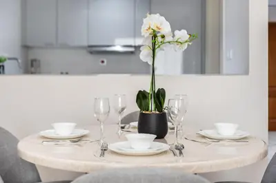 a table with glasses and a vase with flowers on it at 2BR Retreat in the Heart of Dubai Marina by EE Holiday Homes in Dubai