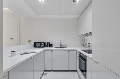 a white kitchen with white cabinets and appliances at 2BR Retreat in the Heart of Dubai Marina by EE Holiday Homes in Dubai