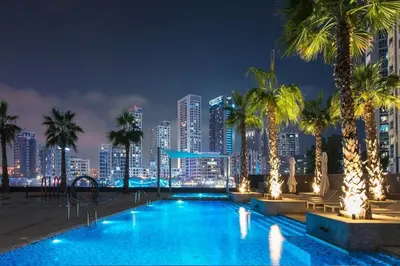 a swimming pool with a city skyline at night at Stylish 1BR in Sparkle Towers Dubai Marina Escape in Dubai